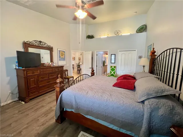 Primary bedroom featuring LVP wood-type flooring, ceiling fan, and a closet