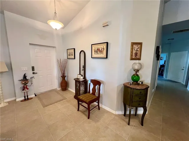 Foyer entrance with light tile patterned floors and high vaulted ceiling