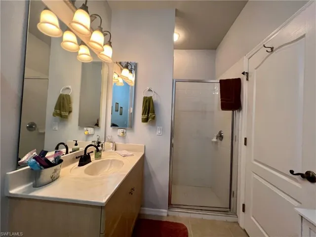 Bathroom featuring tile patterned flooring, walk in shower, and vanity