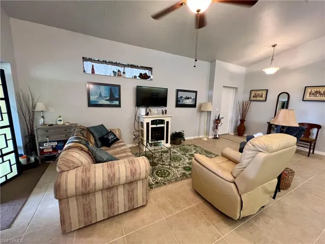 Living room featuring ceiling fan, light tile patterned flooring, and a healthy amount of sunlight
