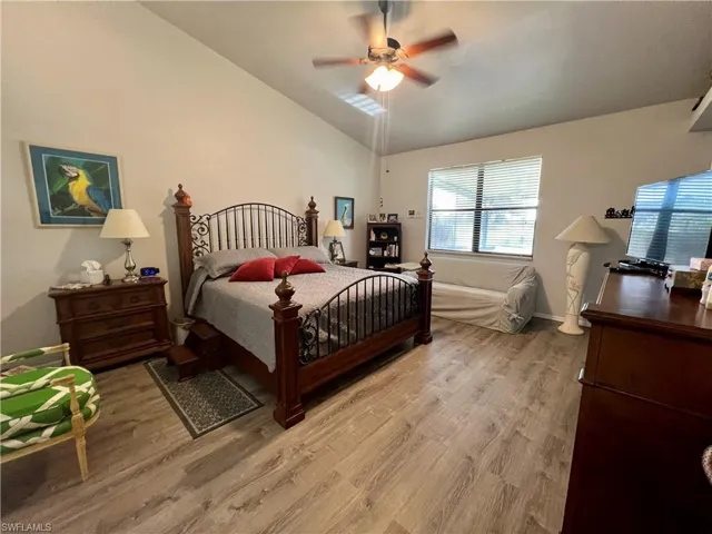 Primary bedroom featuring ceiling fan, lofted ceiling, and light LVP wood-style floors