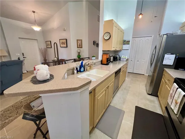Kitchen featuring a kitchen breakfast bar, hanging light fixtures, sink, and high vaulted ceiling