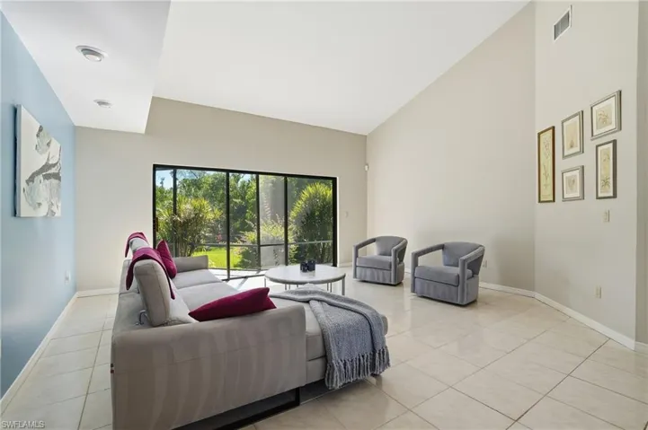 Living area with light tile patterned floors and high vaulted ceiling