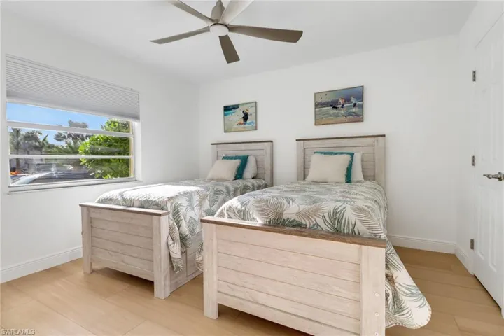 Bedroom featuring light wood finished floors, baseboards, and a ceiling fan