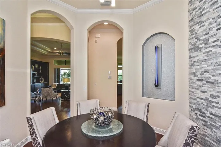 Dining space featuring arched walkways, crown molding, ceiling fan, and wood finished floors