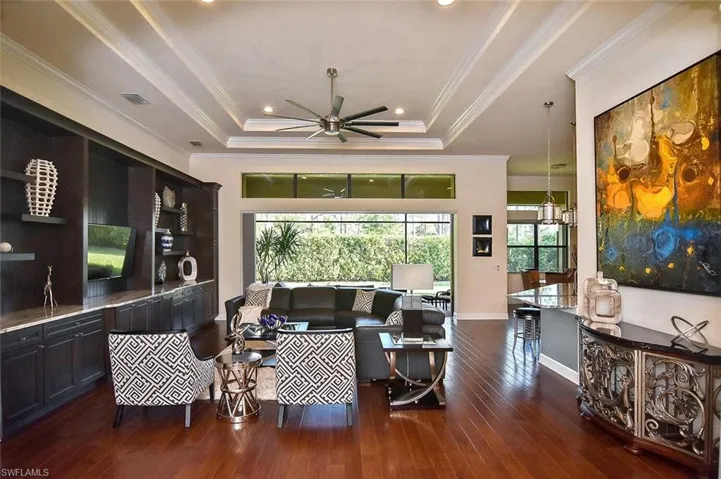 Living room featuring crown molding, dark wood-style flooring, a raised ceiling, ceiling fan, and recessed lighting