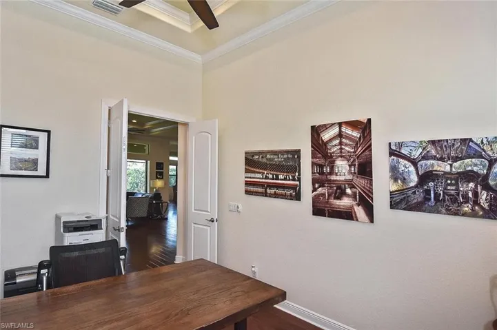 Office area with crown molding, dark wood-style floors, and ceiling fan
