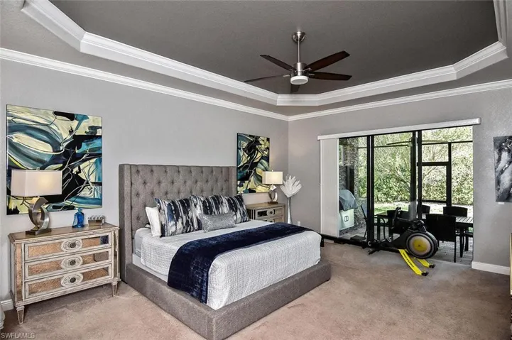 Bedroom with a raised ceiling, ornamental molding, carpet, and a ceiling fan