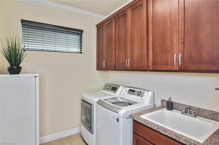 Laundry area featuring ornamental molding, washing machine and dryer, and cabinet space