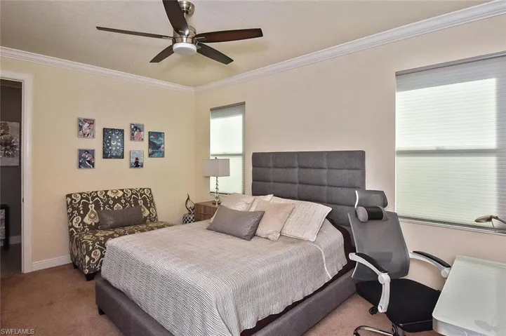 Carpeted bedroom featuring crown molding, ceiling fan, and a textured ceiling