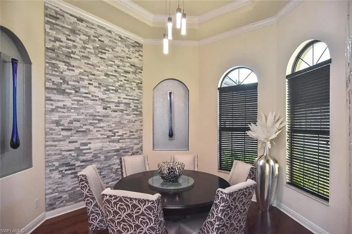 Dining space with dark wood-type flooring, crown molding, and a raised ceiling