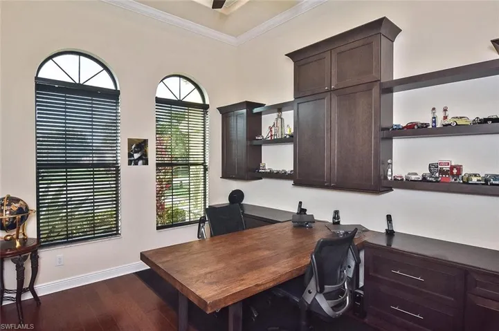 Office area with ornamental molding and dark wood-style floors