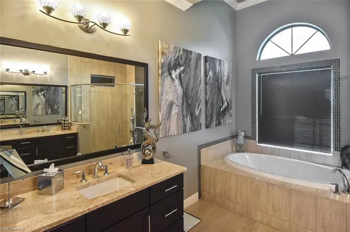 Full bath with vanity, a bath, a stall shower, ornamental molding, and light tile patterned floors