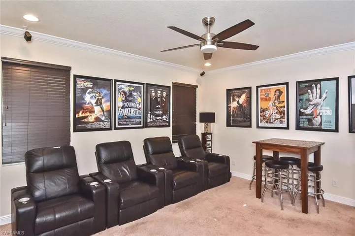 Home theater with ornamental molding, light colored carpet, a textured ceiling, ceiling fan, and recessed lighting