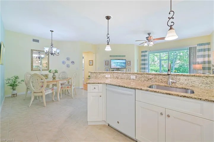 Kitchen featuring hanging light fixtures, light tile floors, sink, and white dishwasher