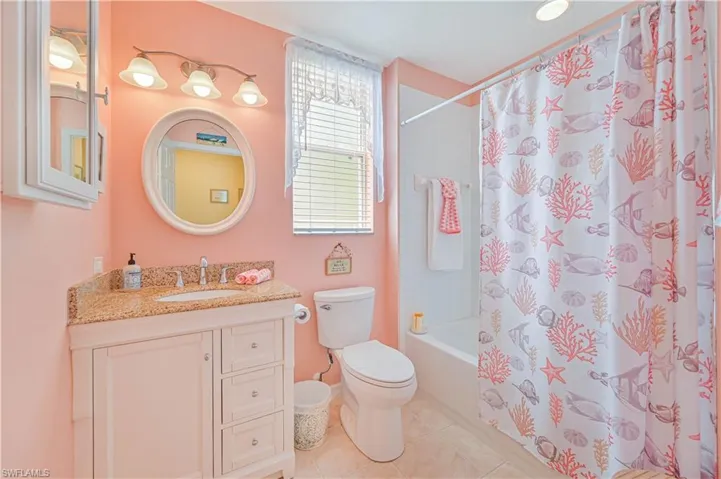 Full bathroom featuring tile floors, shower / bath combination with curtain, toilet, and vanity