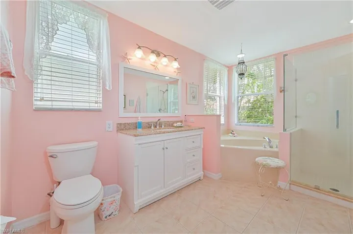 Full bathroom with tile flooring, shower with separate bathtub, toilet, and vanity with extensive cabinet space