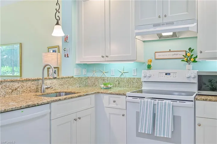 Kitchen featuring decorative light fixtures, white appliances, sink, and white cabinetry