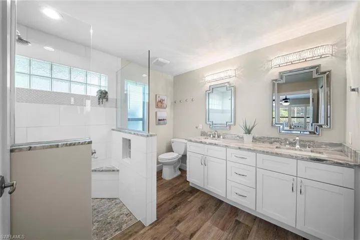Spacious bathroom featuring a frameless glass shower enclosure with a built-in bench, glass block window, and mosaic tile accent