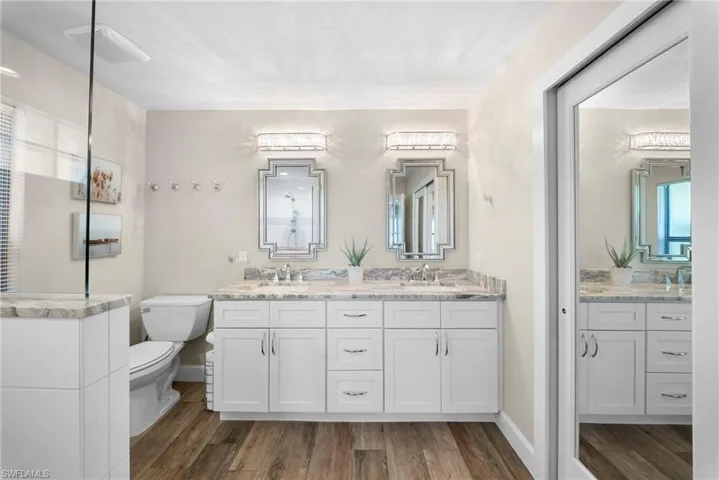 Dual vanity featuring white shaker cabinetry, stone countertops, and ornate framed mirrors