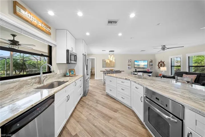 Expansive kitchen featuring white cabinetry, stainless steel appliances, and premium countertops