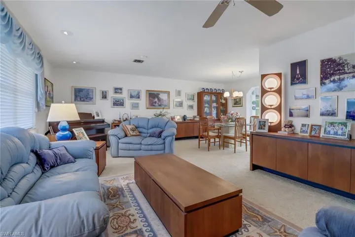 Carpeted living room with ceiling fan with notable chandelier