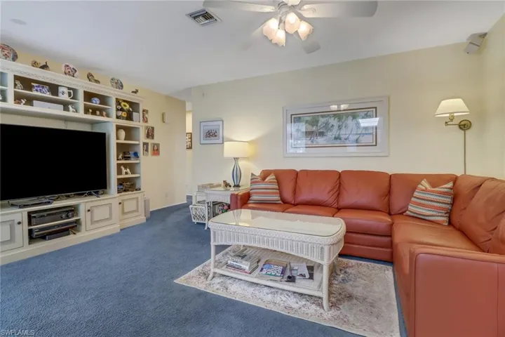 Carpeted living room featuring ceiling fan