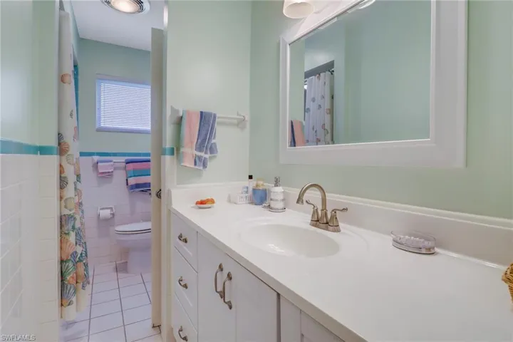 Bathroom featuring tile walls, toilet, tile patterned floors, and vanity