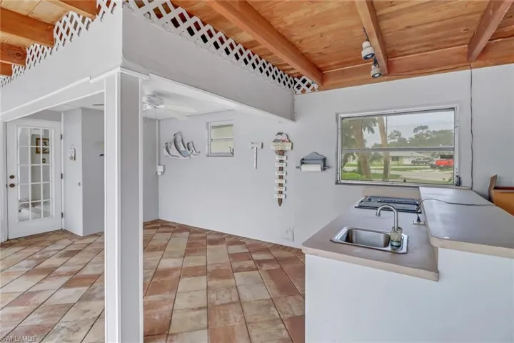 Kitchen with beam ceiling, light tile patterned floors, wood ceiling, and sink