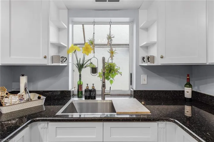 Kitchen featuring white cabinetry, dark granite countertops, and beautiful stainless chef's sink.