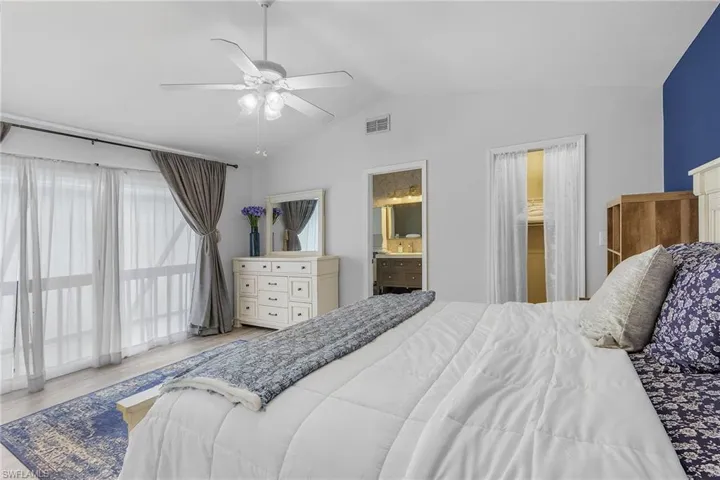 Bedroom featuring connected bathroom, ceiling fan, lofted ceiling, and light hardwood / wood-style floors