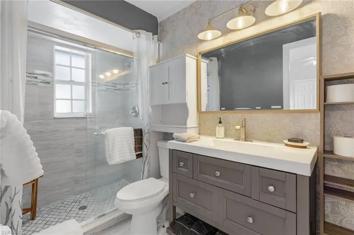 Bathroom featuring vanity, toilet, walk-in shower with a glass shower door