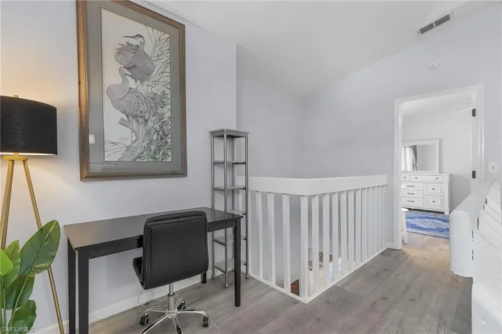 Top of the steps with entry to the Master Retreat offering wood-type flooring and vaulted ceiling