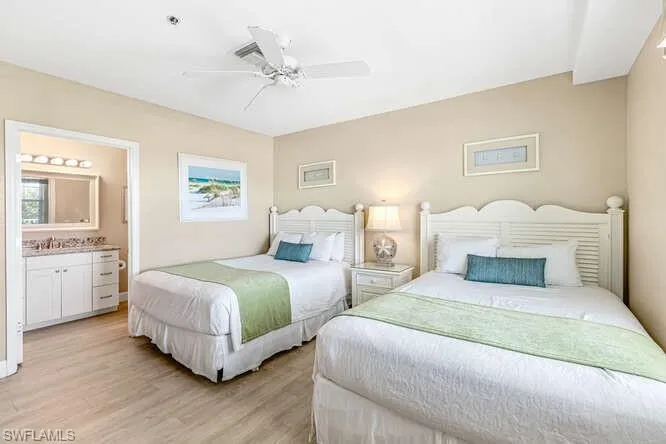 Bedroom with light wood finished floors, ceiling fan, and ensuite bath