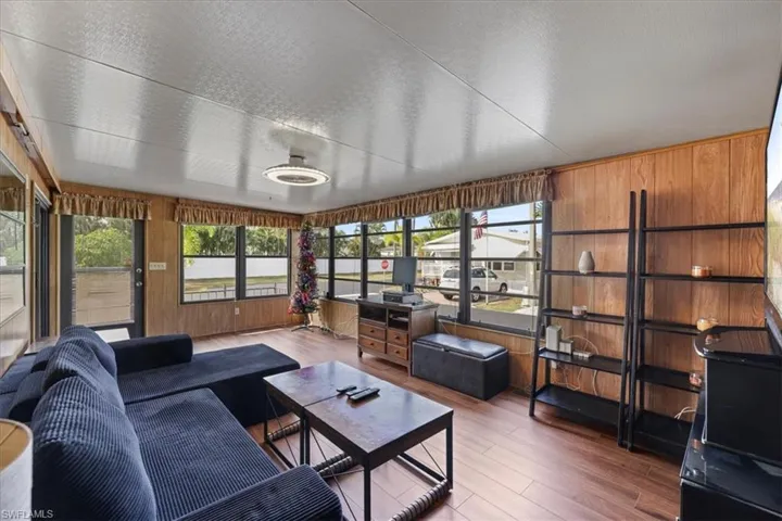 Sunroom / solarium with wood walls, wood finished floors, healthy amount of natural light, and a textured ceiling