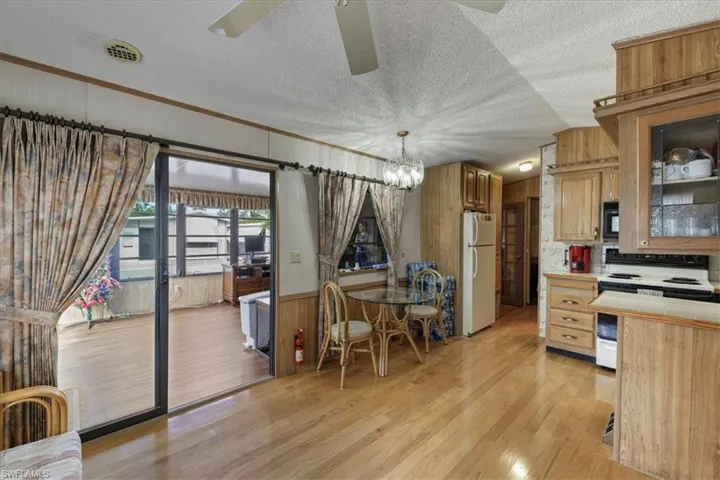 Kitchen with tile countertops, white appliances, a textured ceiling, light wood-type flooring, and a chandelier