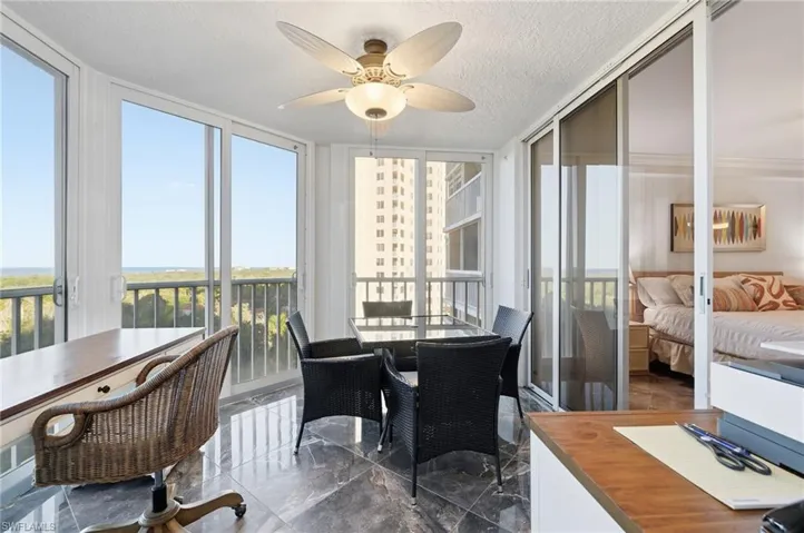 Sunroom / solarium with marble tiled floors, a textured ceiling, a wall of windows, and a water view