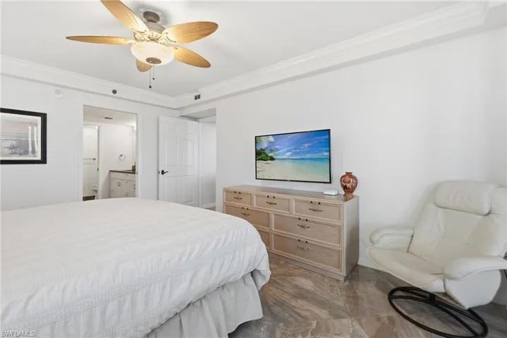 Bedroom featuring ornamental molding, ceiling fan, and ensuite bath