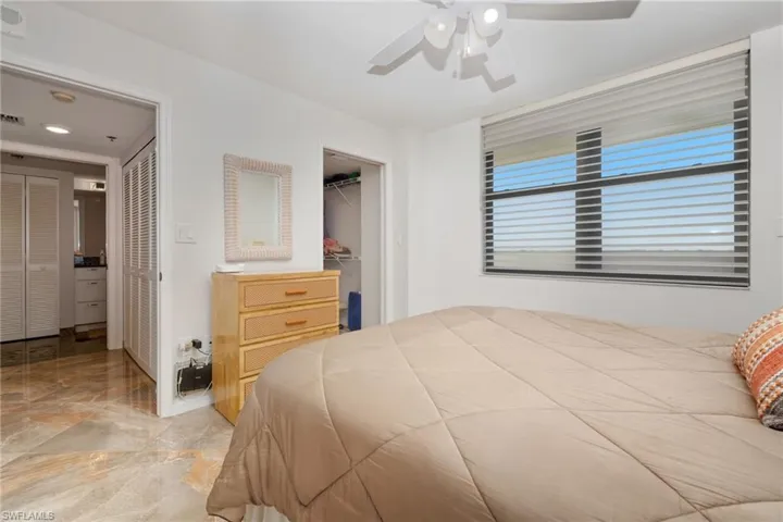 Bedroom with a ceiling fan, a spacious closet, and light marble finish floors