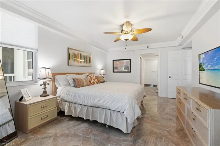 Bedroom with crown molding, ceiling fan, and light marble finish floors