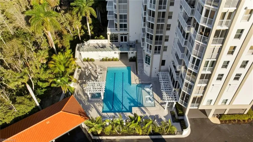 Drone / aerial view of a pool area and apartment complex / building