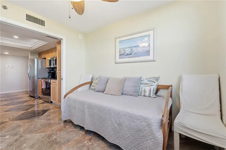 Bedroom featuring recessed lighting, ceiling fan, dark marble finish flooring, a raised ceiling, and freestanding refrigerator