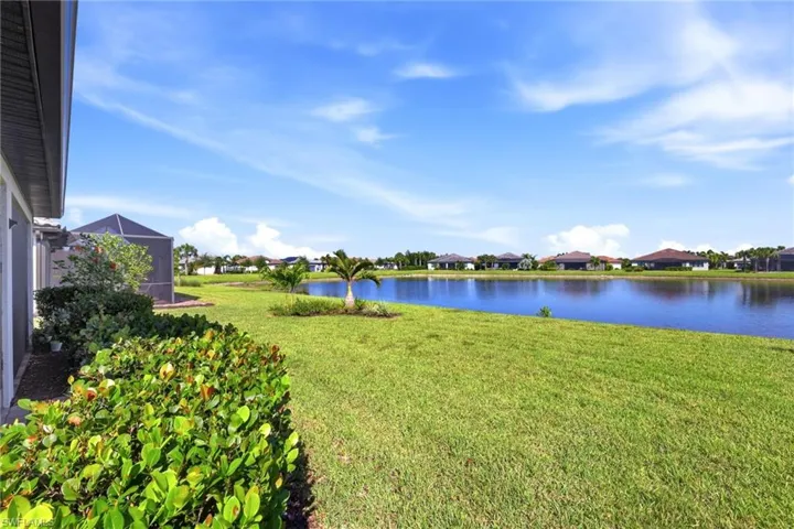 Expansive backyard featuring a manicured lawn, established landscaping, and direct water frontage