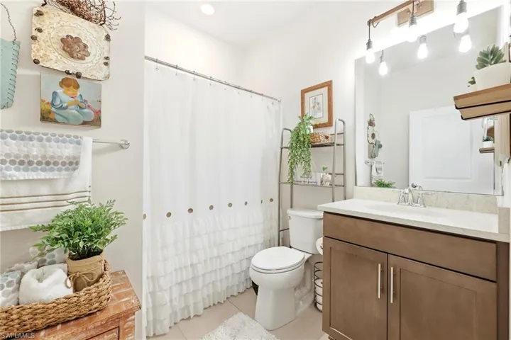 Full bathroom featuring a single vanity with wood-finish cabinetry, a light-toned countertop, and a large mirror with overhead lighting