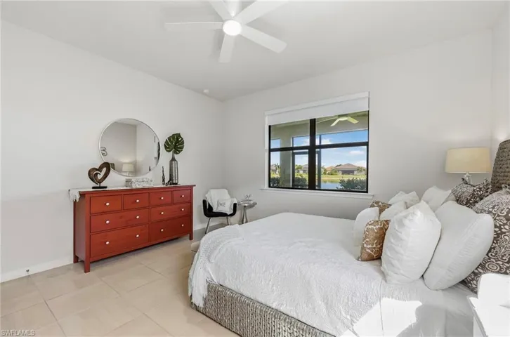 Bright interior space featuring a ceiling fan, a large window with a roller blind, and light tile flooring