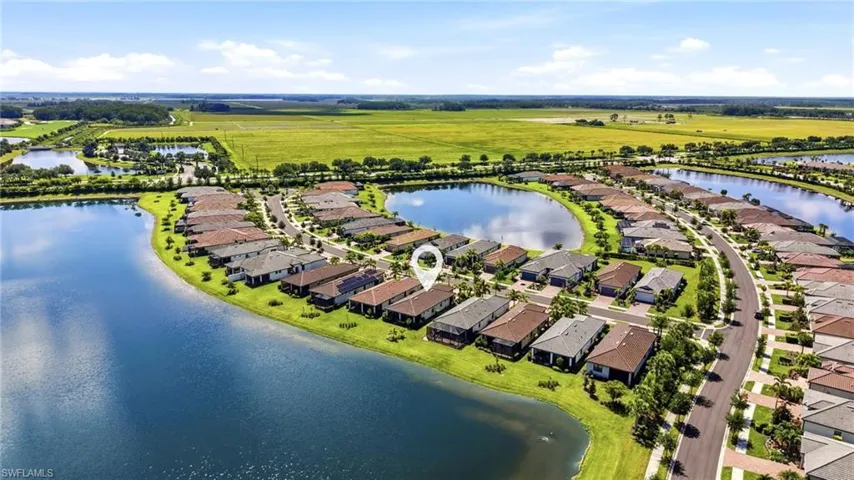 Residential community featuring waterfront properties, mature landscaping, paved roads, and a clear blue sky