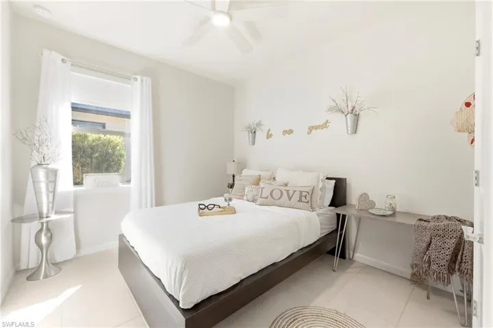 Spacious bedroom featuring light-toned flooring, a window with natural light, a ceiling fan, and ample wall space