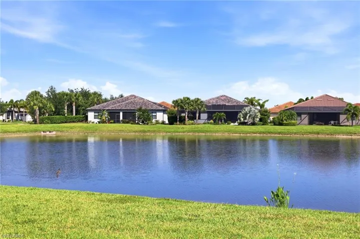 Expansive waterfront property featuring a large body of water, green grassy banks, and mature palm trees