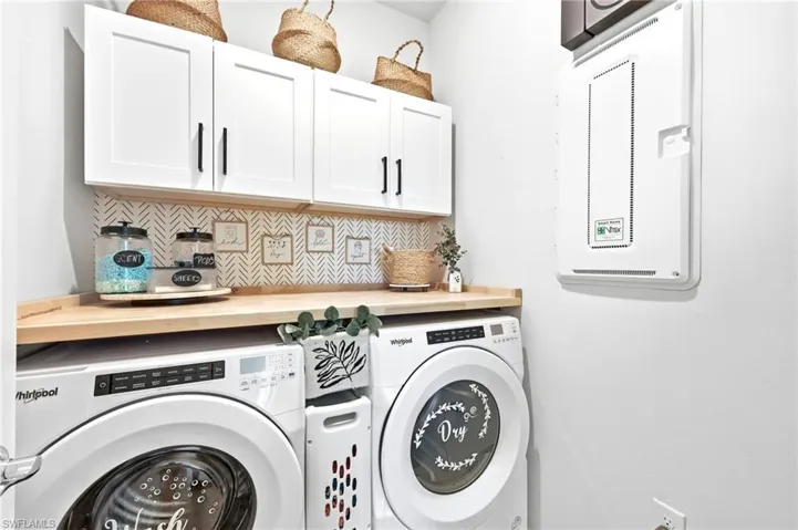 Dedicated laundry area featuring storage between washer/dryer, cabinets above and folding table.  Not pictured is a hanging rack for clothes.