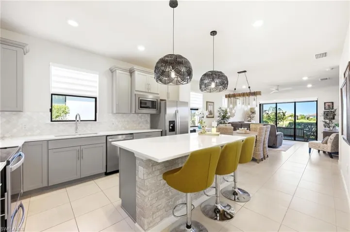 Kitchen featuring light gray cabinetry, stainless steel appliances, white countertops, and a full tile backsplash